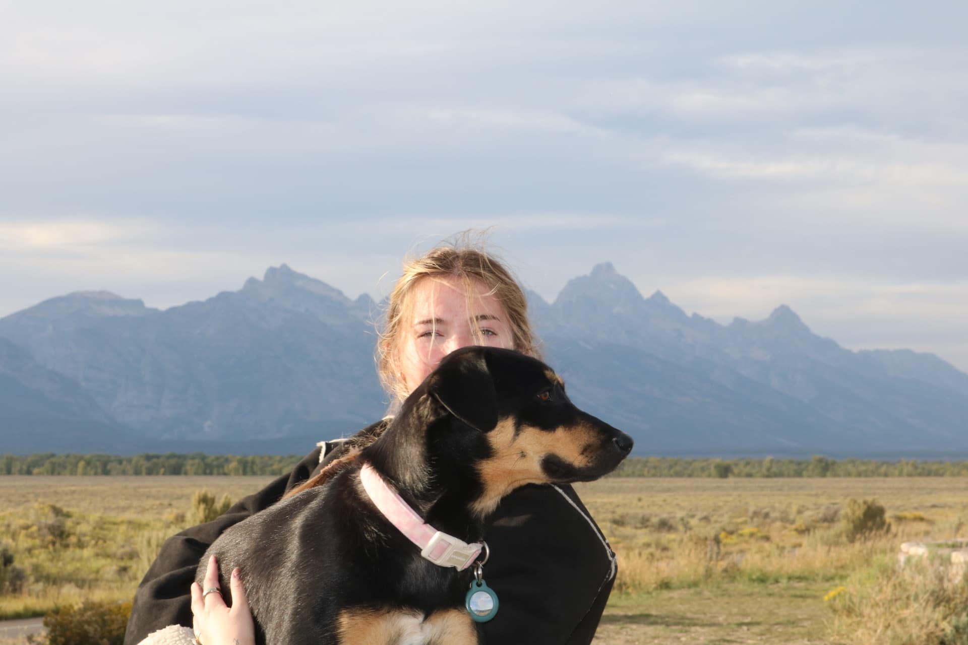 Wife holding the dog with the Tetons behind them