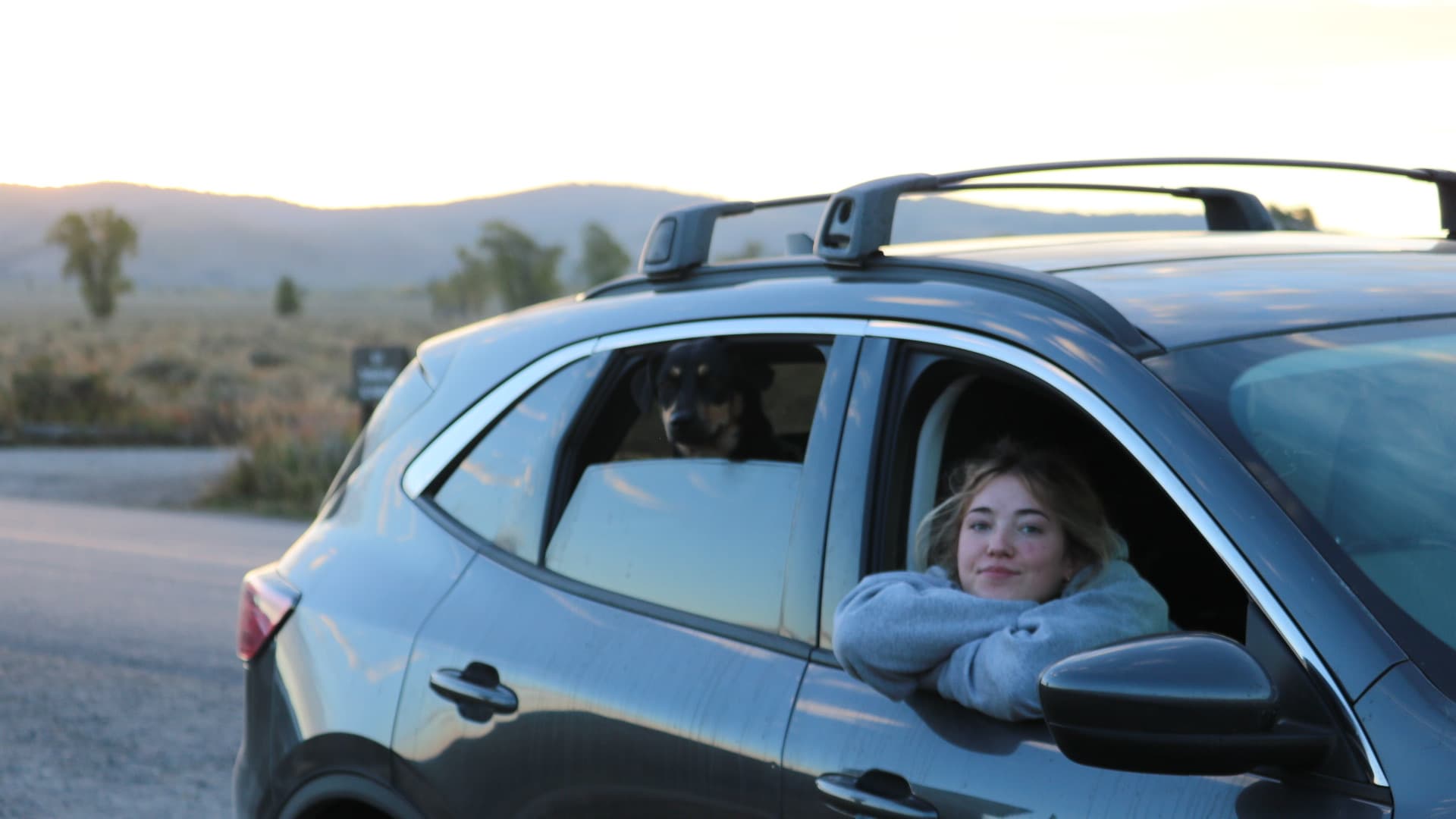 Wife and the dog riding with the windows down at sunset